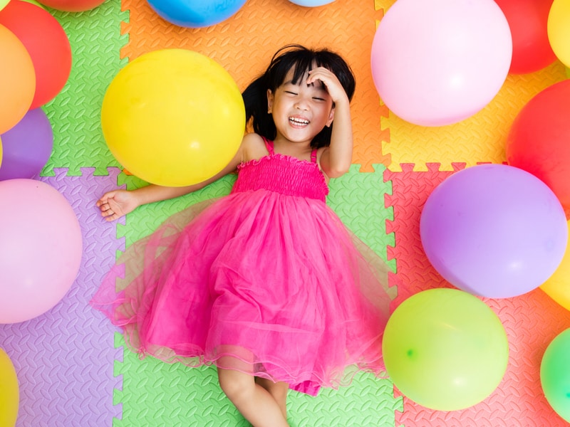 Child lying on a colourful mat laughing in delight