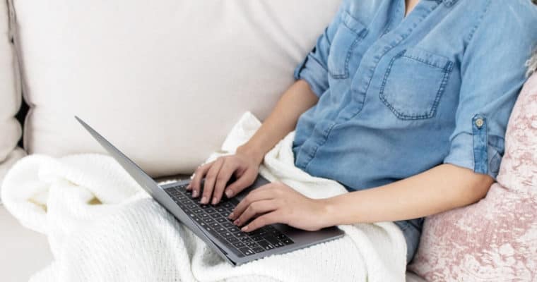 Woman seated on a couch with a laptop and working from home