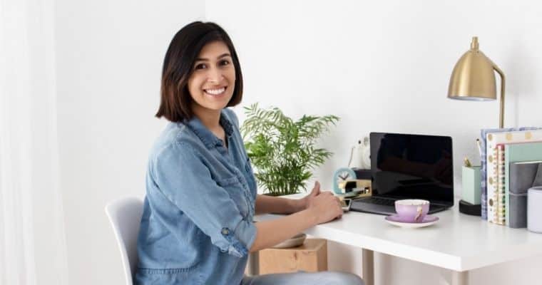 Successful Blogging secret featuring a smiling woman blogger seated at her desk with a laptop